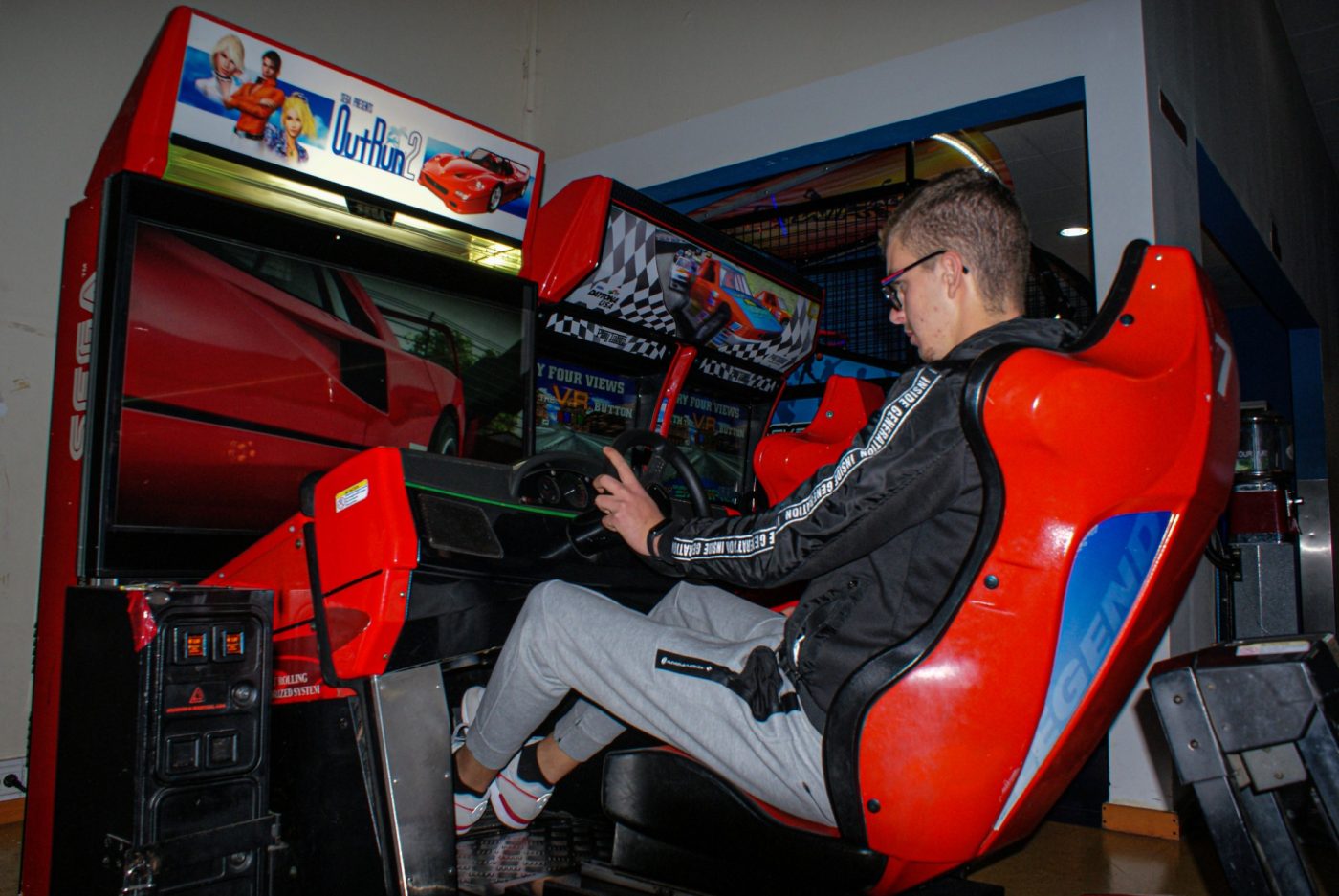 Jovem numa máquina de corridas de arcade na sala de jogos